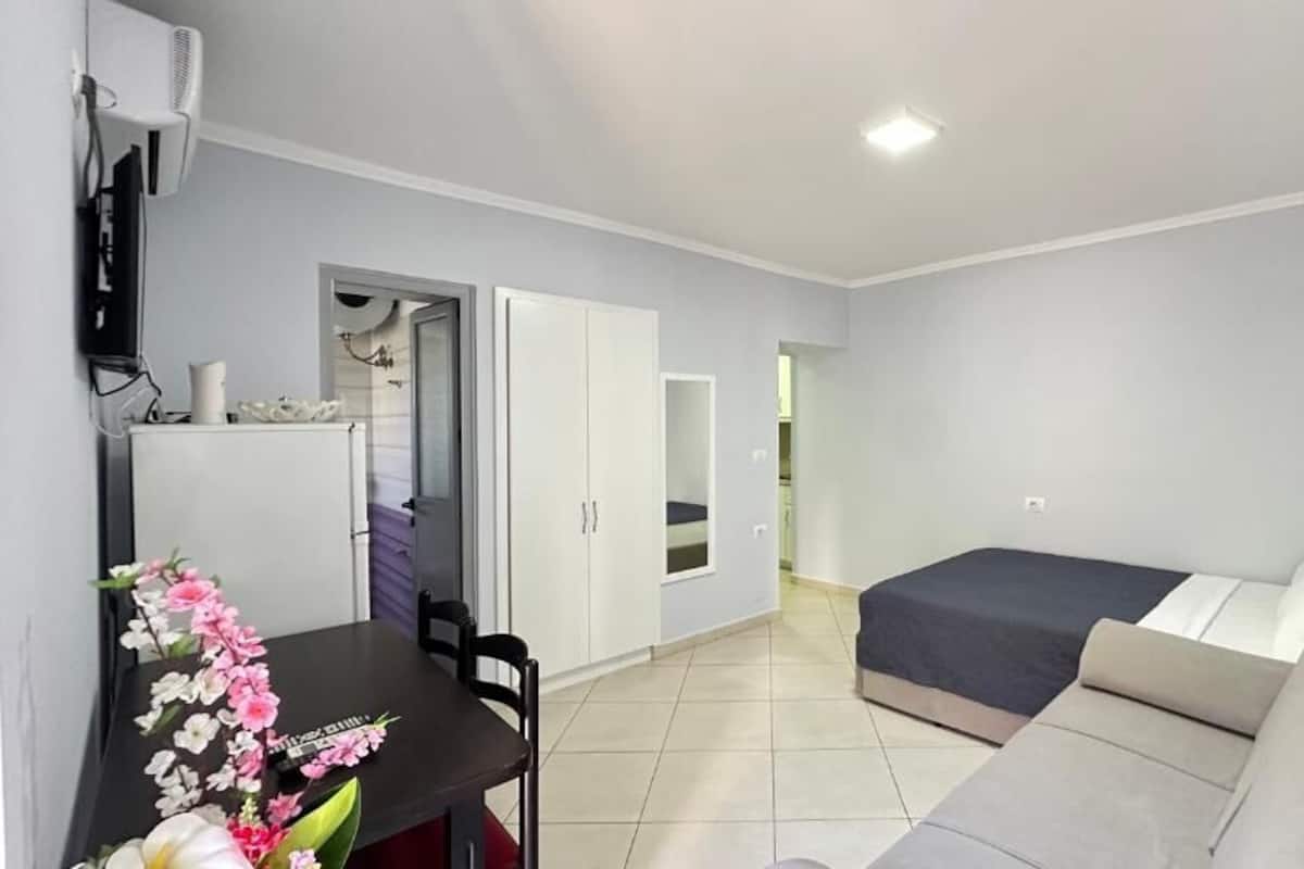 A compact hotel room with a bed, a sofa, a desk, and a TV.
