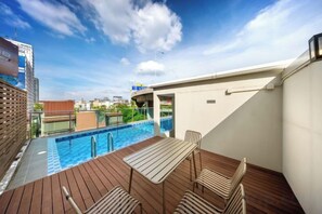 A rooftop pool area with a wooden deck, lounge chairs, and a view of the cityscape. - Ralph Poshtel Pratunam (Bangkok)