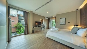 A modern hotel room with a large bed, a desk, and a view of the outdoors.