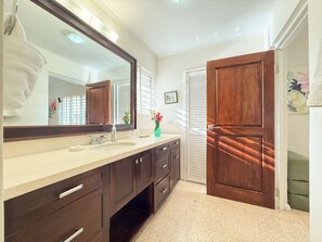 Un baño con un espejo grande, un lavabo y una puerta de madera.