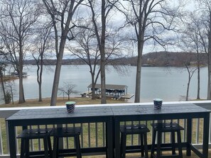 Une terrasse avec vue sur un lac, un quai et une maison.