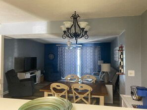 A dining area with a table, chairs, a chandelier, and a television in the background. - Lakefront! 2-bedroom townhome at Smith Mountain Lake (Moneta)