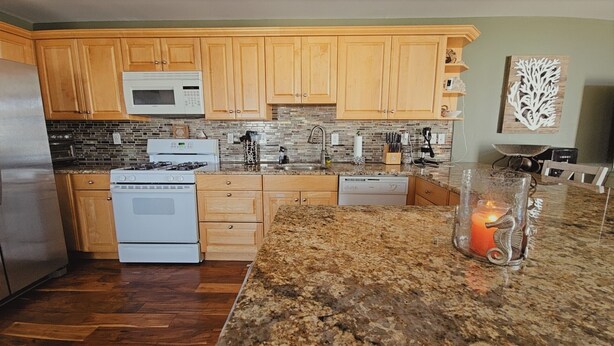 A modern kitchen with wooden cabinets, a granite countertop, a microwave, a stove, and a dishwasher. - 3-bedroom townhome in beautiful North Wildwood with AC two blocks from the beach (North Wildwood)