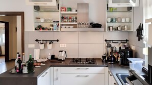 A modern kitchen with white cabinets, a gas stove, and various kitchen appliances. - Lovely apartment in Hreljin (Hreljin)
