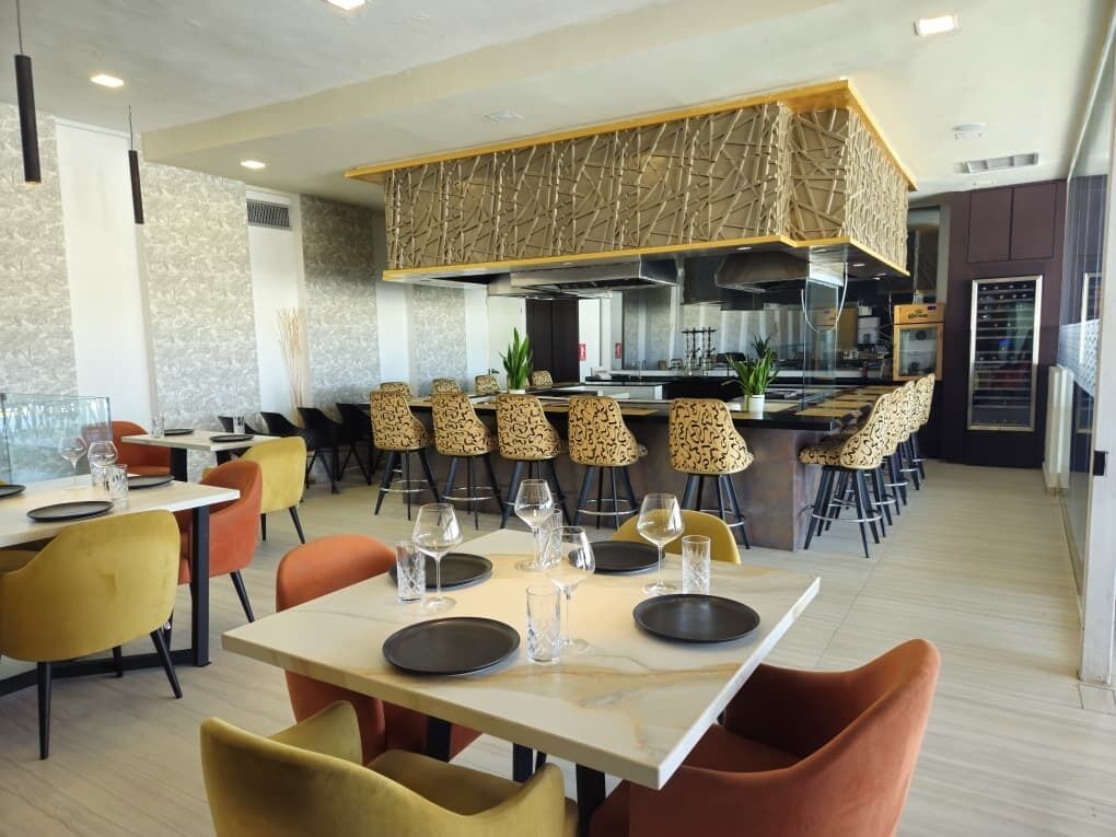 Ein modernes Restaurant mit Barbereich, mehreren Tischen und Stühlen.