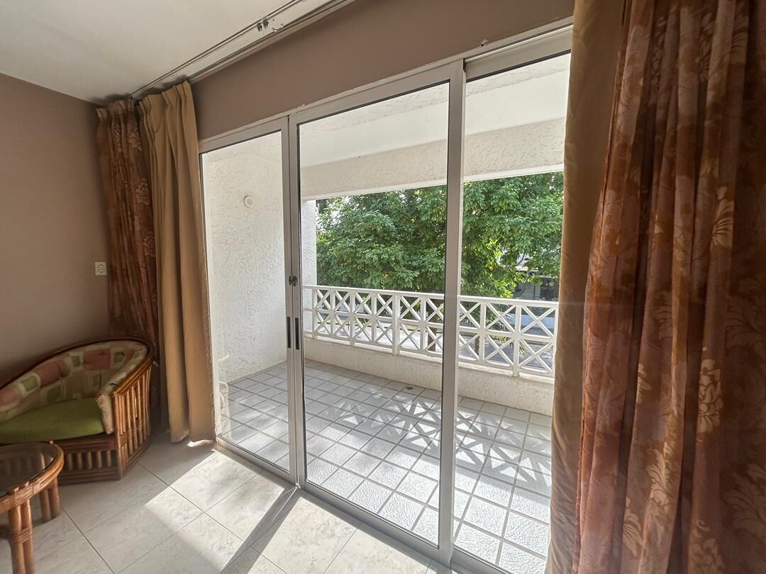 A room with a sliding glass door leading to a balcony with a white railing.