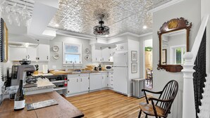 Una cocina moderna con armarios blancos, una mesa de comedor de madera y una araña.