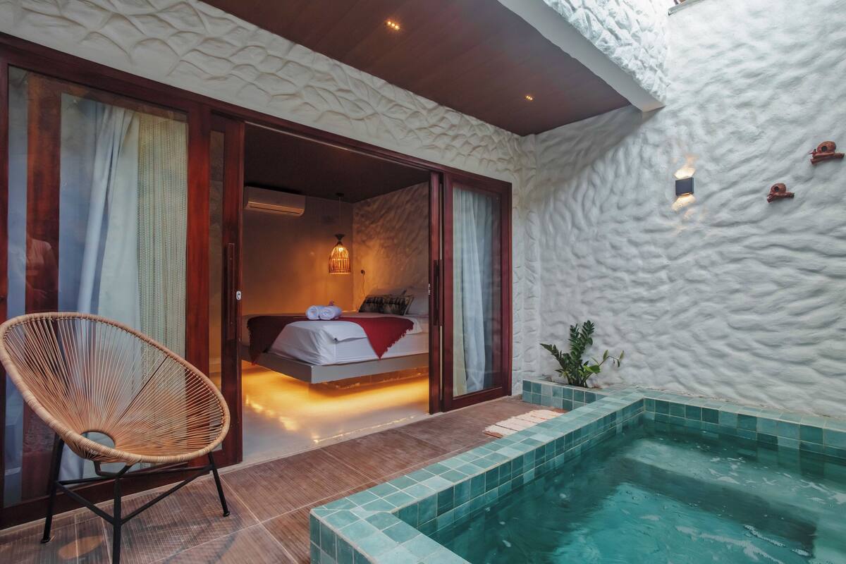 Un dormitorio con cama, una silla y una pequeña piscina.