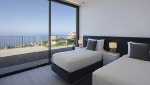 Una habitación de hotel moderna con un balcón grande, dos camas y vistas al mar.