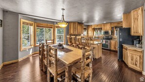 A spacious kitchen with wooden cabinets, a central island, and a dining table with chairs. - The Lost Creek Lodge - A Perfect Escape for Families, Reunions, and Friends. (Duck Creek Village)