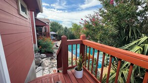 A wooden deck with a potted plant, a stone pathway, and a view of a swimming pool.