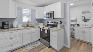 A modern kitchen with white cabinets, a built-in oven, a microwave, and a coffee maker. - LOCATION!! LOCATION!!  SHORT WALKING TO RESTAURANTS, SHOPS, & BEACH! (Fort Myers Beach)