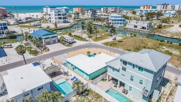A coastal residential area with modern buildings, a swimming pool, and a beach in the background. - LOCATION!! LOCATION!!  SHORT WALKING TO RESTAURANTS, SHOPS, & BEACH! (Fort Myers Beach)