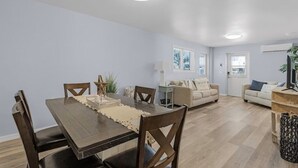A modern living room with a wooden dining table, two sofas, and a TV. - LOCATION!! LOCATION!!  SHORT WALKING TO RESTAURANTS, SHOPS, & BEACH! (Fort Myers Beach)