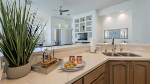 A modern kitchen with a central island, built-in shelves, and a large potted plant.