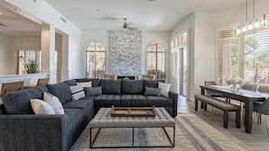 A spacious living room with a sectional sofa, a dining table, and a stone accent wall.