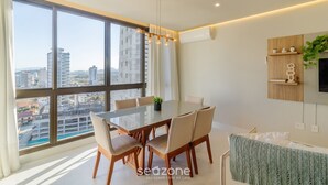 A modern dining area with a large window, a glass table, and beige chairs. - Well-equipped Apartments 100m From the Beach - EVR (Porto Belo)