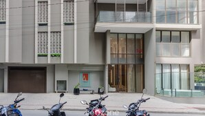A modern building with a glass entrance, potted plants, and parked scooters. - Well-equipped Apartments 100m From the Beach - EVR (Porto Belo)