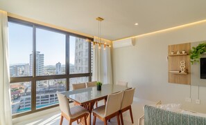 Une salle à manger moderne avec une grande fenêtre, une table à manger, des chaises et une plante en pot.