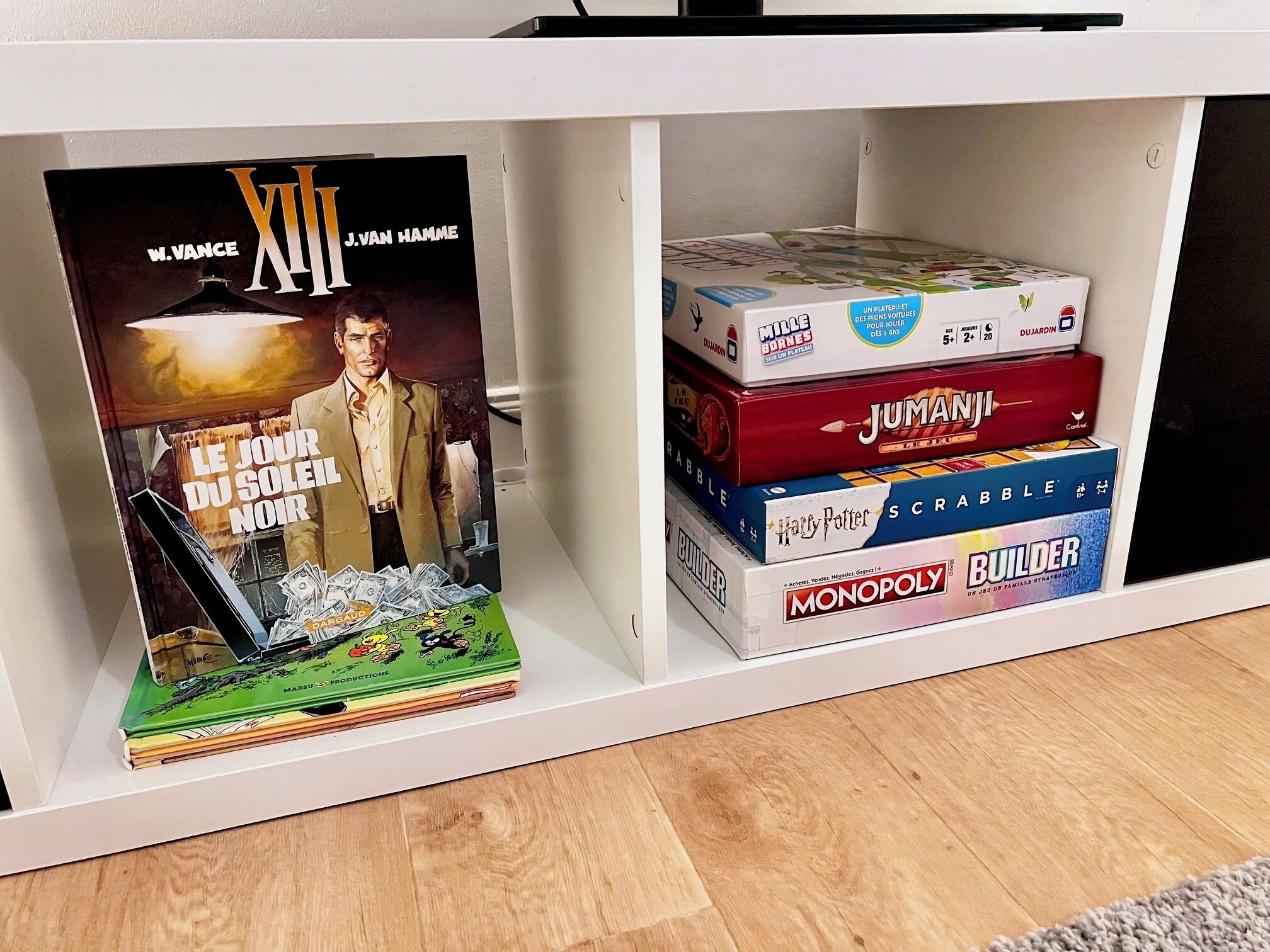 En hylla med en hög brädspel, bland annat Monopol, Jumanji och Scrabble.