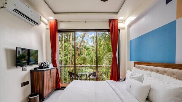 Quarto de hotel com uma cama, televisão, escrivaninha e vista para o exterior.