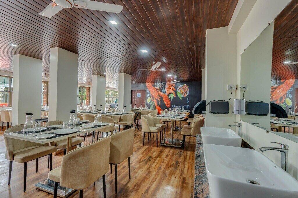 Restaurante com chão de madeira, várias mesas montadas com copos e um mural retratando frutos do mar.