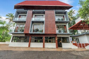 Un edificio de varios pisos con techo rojo, balcones y ventanas grandes.