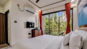 Quarto de hotel com cama, televisão, escrivaninha e janela com cortinas vermelhas.