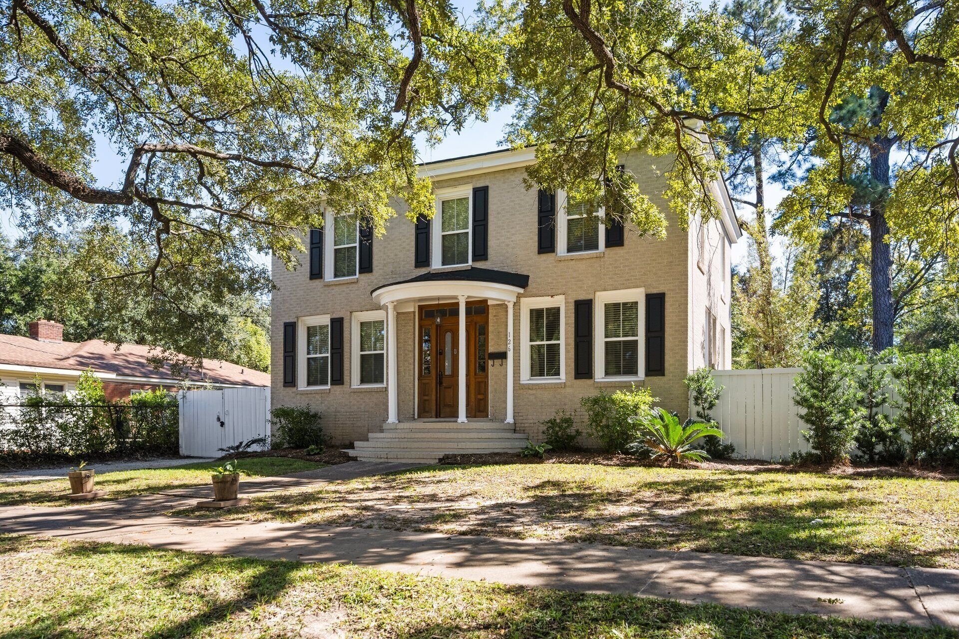 A two-story brick house with a front porch, a garage, and a well-maintained lawn.