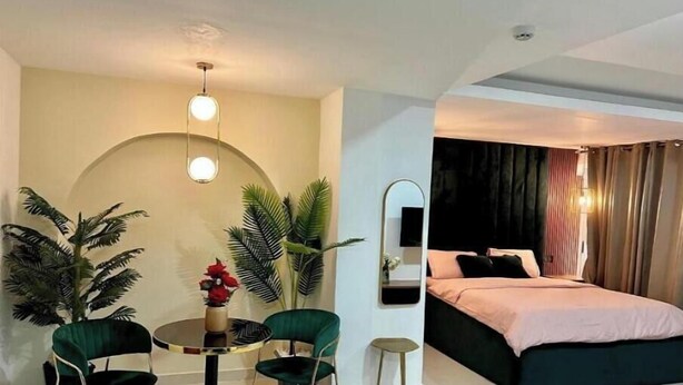 Une chambre d’hôtel avec un lit, une table ronde entourée de chaises et un petit miroir.