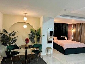 Una habitación de hotel con una cama, una mesa redonda con sillas y un espejo pequeño.