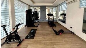 Une salle de sport équipée de matériel d’exercice, dotée d’un plancher en bois et de grandes fenêtres.