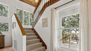 A staircase with wooden steps and a wooden handrail, leading to a balcony with a railing. - Charming Coastal Retreat sleeps up to 9 (Fernandina Beach)