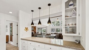 A kitchen with white cabinets, granite countertops, and pendant lighting. - Charming Coastal Retreat sleeps up to 9 (Fernandina Beach)