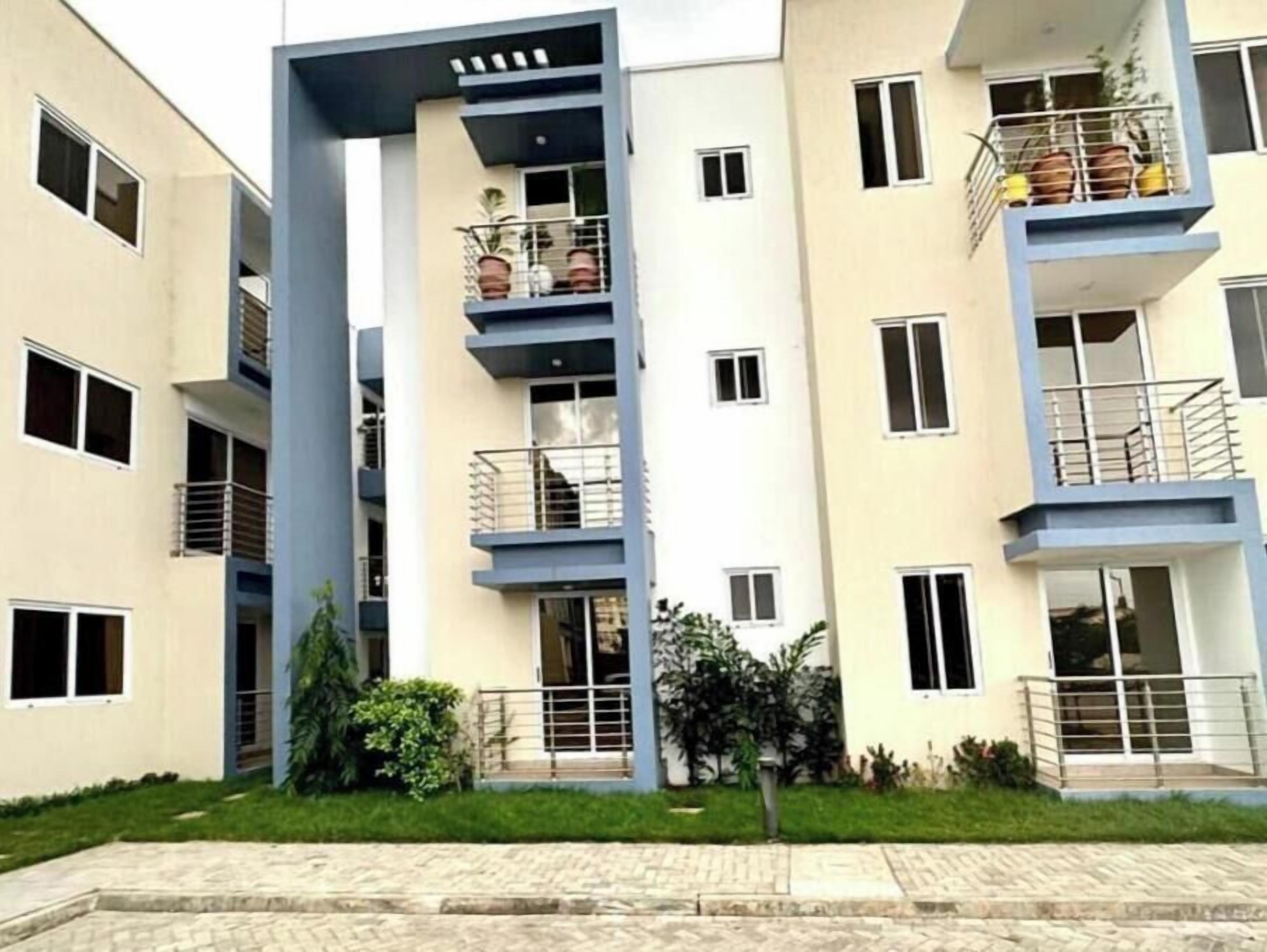 A multi-story residential building with balconies, a central stairwell, and a paved courtyard.