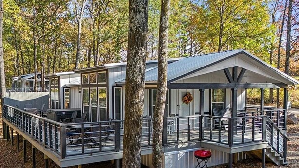 Une cabane dotée d’une terrasse, de meubles de jardin et d’un porche abrité.