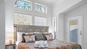 Une chambre à coucher avec un grand lit, de nombreuses fenêtres et une porte.