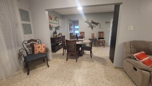 Una sala de estar con comedor, un sofá, un banco y una mesa.