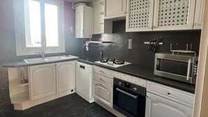 Een moderne keuken met witte kastjes, een zwart aanrecht, een ingebouwde magnetron en een vaatwasser.