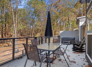 Une terrasse extérieure avec une table et des chaises, un barbecue et un espace abrité avec un parasol.