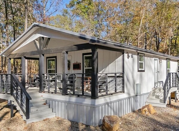Une cabane dotée d’un porche couvert, de nombreuses fenêtres et d’un escalier menant à l’entrée.