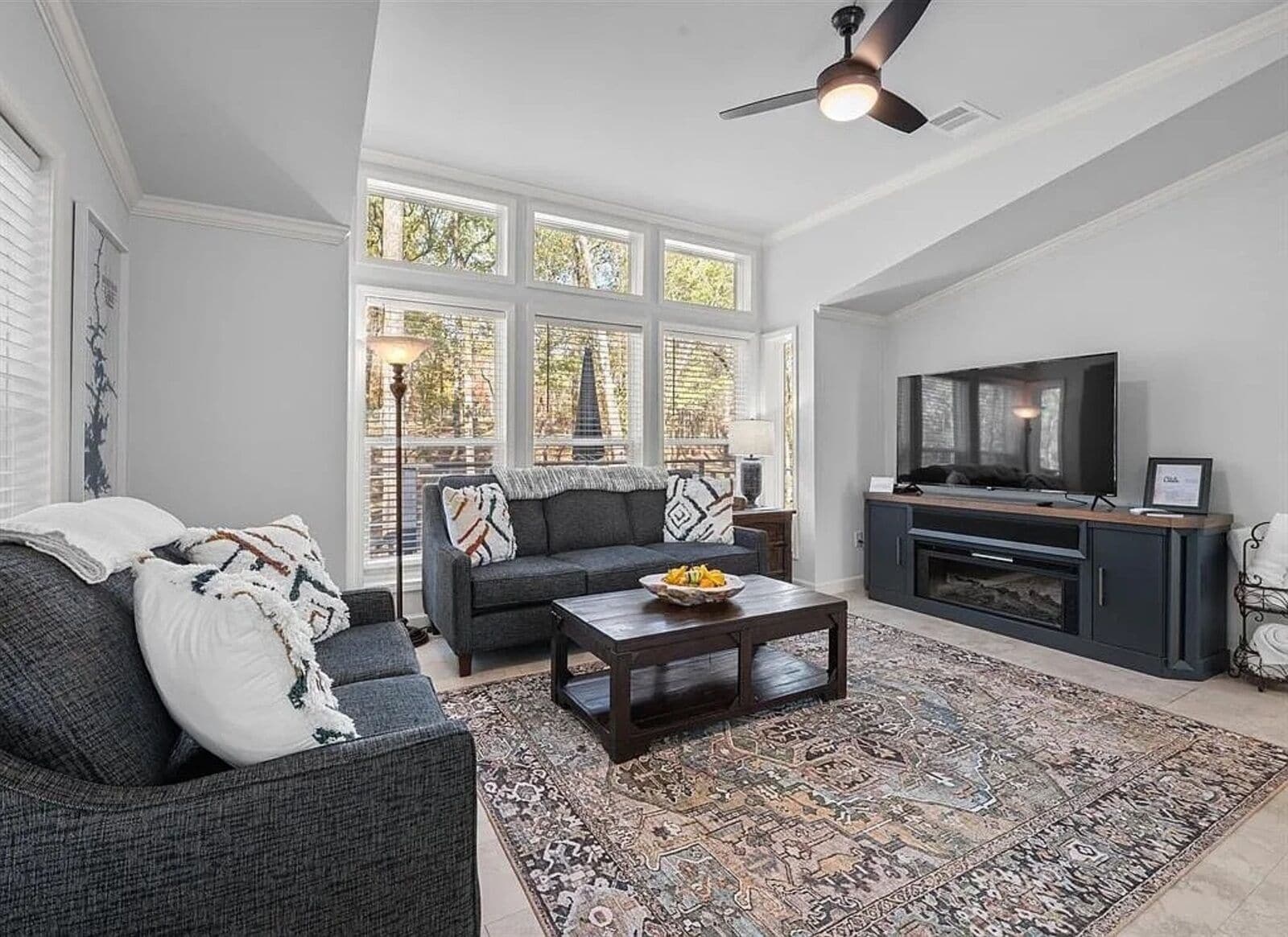 A living room with a dark gray sofa, a coffee table, and a large window with multiple panes.