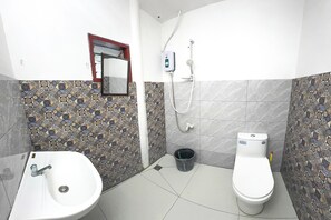A bathroom with a sink, toilet, and shower. The walls are tiled with a patterned design. - Monaliza Surf Resort By Zuzu (San Juan)