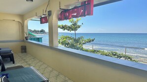 A balcony with a view of the sea, a table with chairs, and a potted plant. - Monaliza Surf Resort By Zuzu (San Juan)
