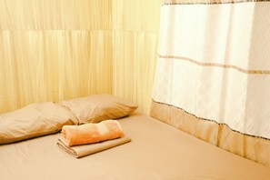 A neatly made bed with beige bedding, a rolled-up towel, and two pillows. - Monaliza Surf Resort By Zuzu (San Juan)