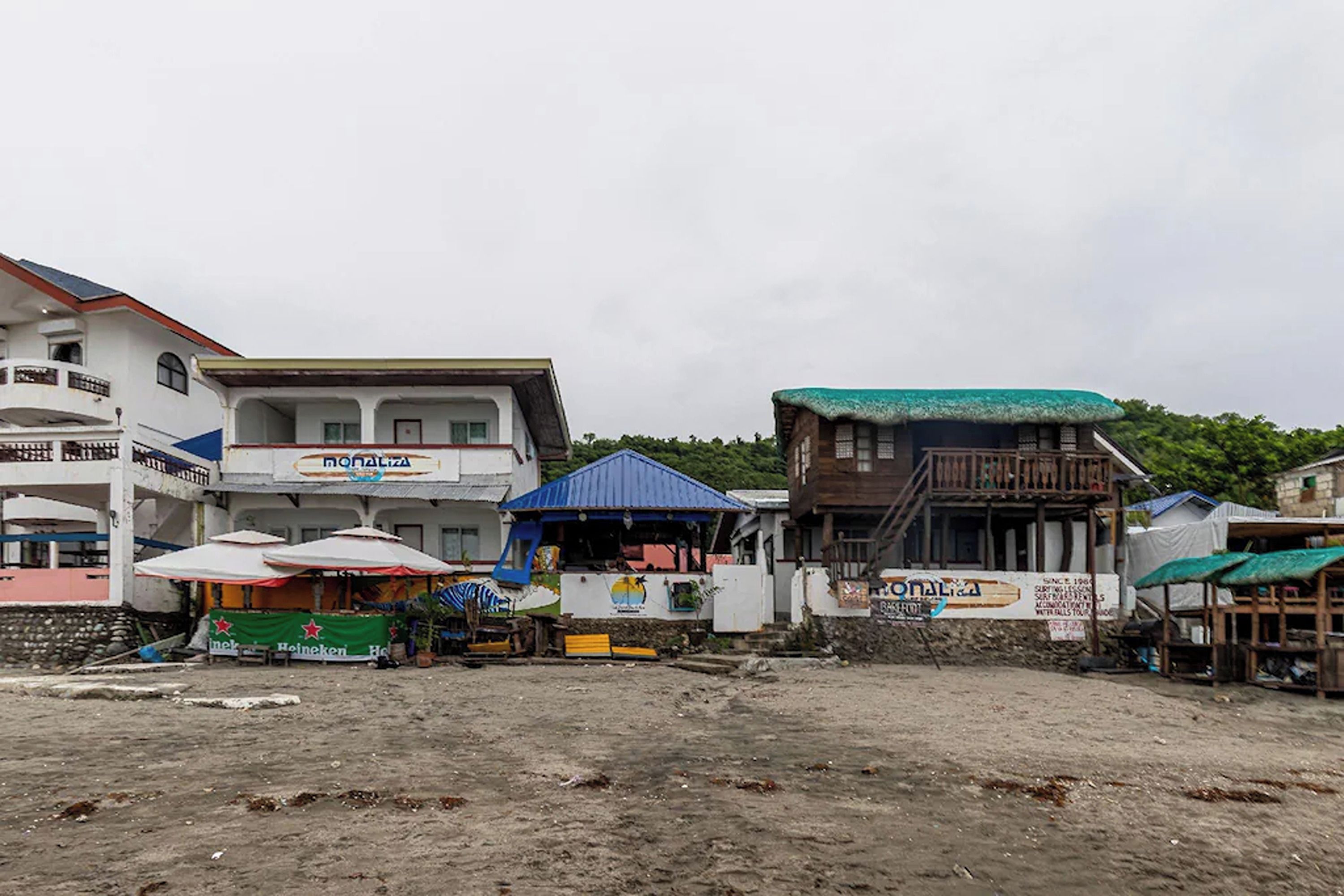 A beachfront area with buildings, including a hotel with a sign for 'Montalta' and a beachside kiosk with umbrellas.