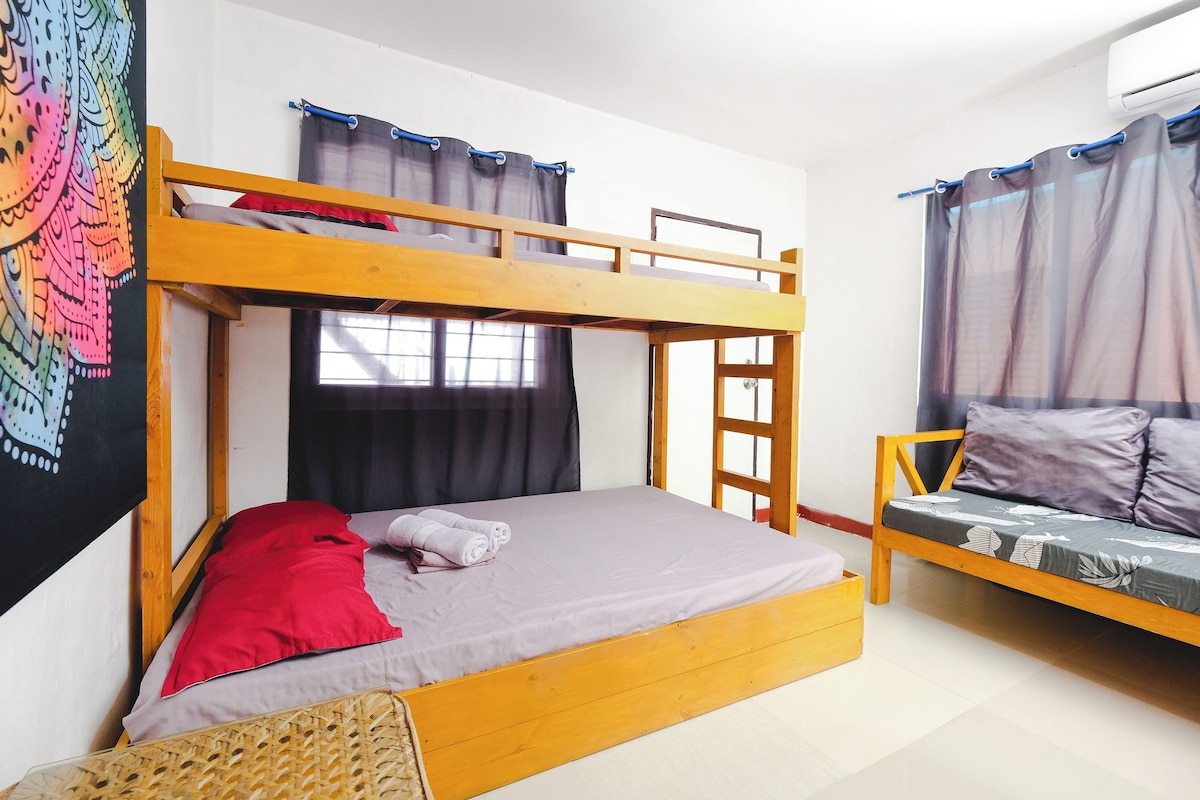 A bunk bed with a ladder, a sofa, and a window with curtains.