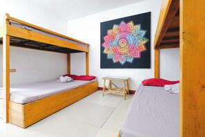 A room with two wooden bunk beds, a small table, and a colorful mandala artwork on the wall. - Monaliza Surf Resort By Zuzu (San Juan)