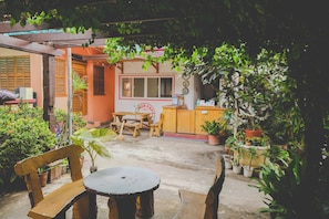 An outdoor patio with wooden furniture, potted plants, and a building with a sign that reads "NATURAL FARM." - Monaliza Surf Resort By Zuzu (San Juan)