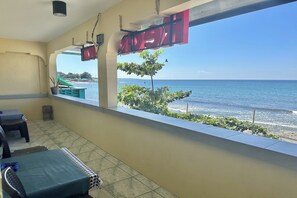 A balcony with a view of the sea, a table with chairs, and a potted plant. - Monaliza Surf Resort By Zuzu (San Juan)